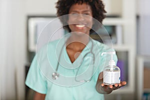 cheerful female nurse holding forwards hand sanitiser