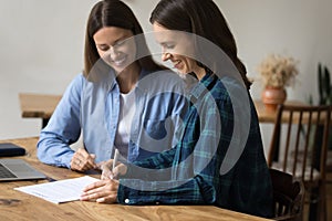 Cheerful female project partners signing contract, meeting at work table