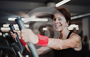 A cheerful female senior in gym doing cardio workout.