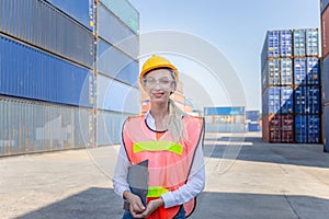 Cheerful female shipping company workers working at the harbor, Women engineer smiling in hardhat and safety vest holding