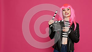 Cheerful female videomaker holding film slate and saying action