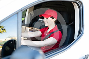 Cheerful female worker sitting behind the wheel of a delivery truck