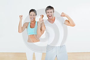 Cheerful fit couple clenching fists in fitness studio