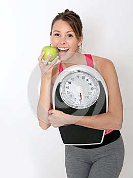 Cheerful fitness girl with green apple succeeding diet