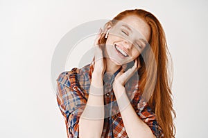 Cheerful foxy girl rejoicing listening music in headphones smiling