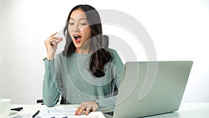 Cheerful freelance Asian woman thinking get idea work using laptop pc on desk over white background. Student young girl use