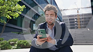 Cheerful freelancer looking cellphone with smile sitting urban stairs close up.