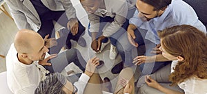 Cheerful and friendly team of office colleagues sitting in circle and chatting during work break.