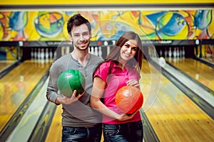 Cheerful friends at the bowling alley with the balls.