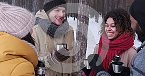Cheerful friends drinking tea in snowy forest