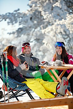 Cheerful friends having fun after skiing in resort with snow equipment
