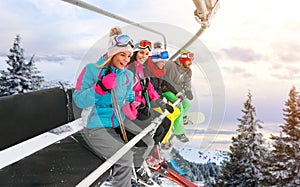 Cheerful friends are lifting on ski-lift for skiing in the mount