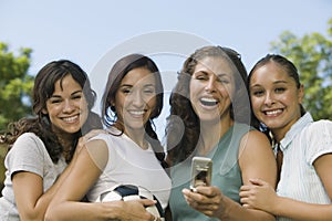 Cheerful Friends With Mobilephone And Soccer Ball At Park