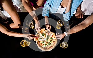 Cheerful friends in the pub. Drinking beer, eating pizza, talking, having fun.