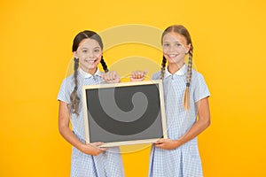 Cheerful friends in retro uniform. vintage kid fashion. back to school. small girls hold blackboard. children education