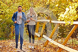 Cheerful friends running in the autumn forest or park