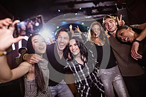 Cheerful friends taking selfie while enjoying at nightclub