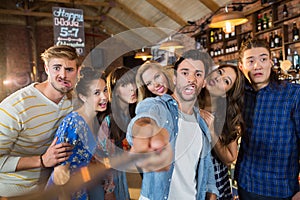 Cheerful friends taking selfie in pub