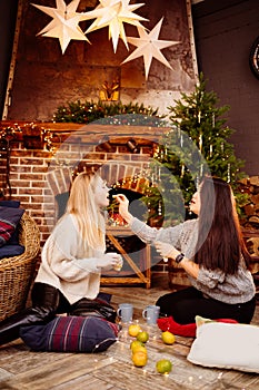 cheerful friends with tangerines in the New Year& x27;s decorations in the fireplace