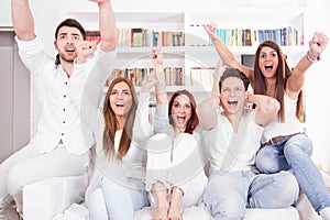 Cheerful friends watching football game on tv