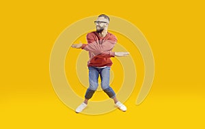 Cheerful, funny and energetic man showing humorous joking dance moves on orange background.