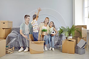 Cheerful funny family playing and having fun in their new house full of cardboard boxes