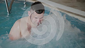 Cheerful funny man swimming in jacuzzi pool.