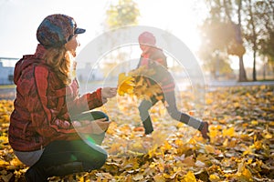 Cheerful and funny mother plays with yellow maple leaves