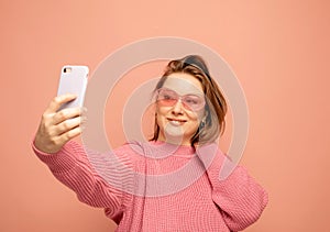 Cheerful funny woman 40s wearing casual sweater posing doing selfie shot on mobile phone over pink background