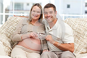 Cheerful future parents holding a sonogram