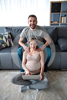 Cheerful future parents resting in living room