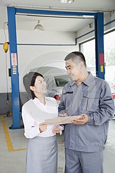 Cheerful Garage Mechanic Explaining to Customer and Showing Her the Bill
