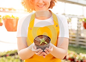 Cheerful gardener with potted sprout