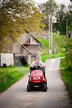 Cheerful gardener riding tractor mower