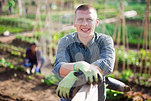 Cheerful gardener standing at smallholding during spring works