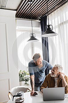 Cheerful gay couple holding hands near