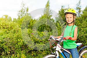 Cheerful girl with braids in helmet holds bike