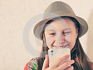 Cheerful girl in cap and making selfie on smartphone.