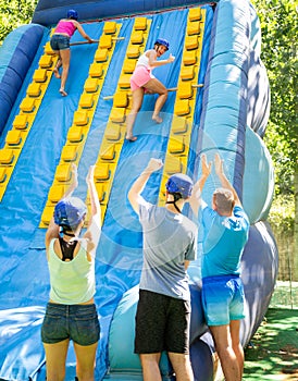 Cheerful girl climbing on inflatable slide with wooden poles