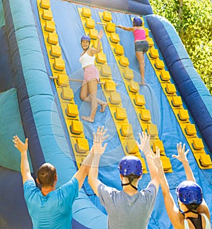 Cheerful girl climbing on inflatable slide with wooden poles