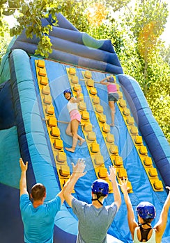 Cheerful girl climbing on inflatable slide with wooden poles