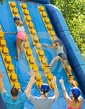 Cheerful girl climbing on inflatable slide with wooden poles