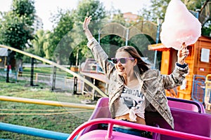 Cheerful girl with cotton candy riding a roller coaster