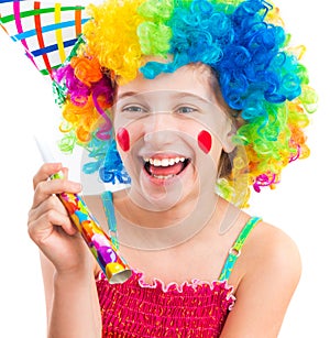 Cheerful girl in curly clown wig and party horn blower