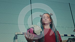 Cheerful girl football player tosses soccer ball in hand with confident movements