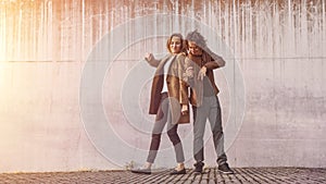 Cheerful Girl and Happy Young Man with Long Hair are Actively Dancing on a Street next to an Urban