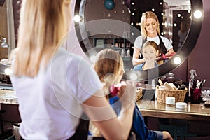 Cheerful girl having her hair brushed in a beauty salon