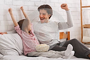 Cheerful girl and her dad watching football match on tv