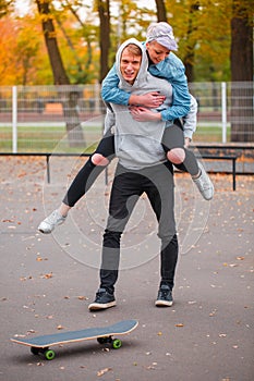 The girl jumped from behind on the guy in the skate park