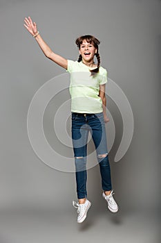 Cheerful girl jumping isolated grey background